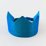 A blue velvet crown-shaped headband with a matching elastic band, photographed on a clean white background.