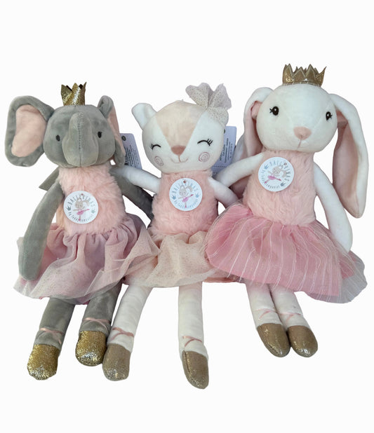 Three plush toys, an elephant, a rabbit, and a mouse, wearing pink dresses and gold shoes on a light pink background.
